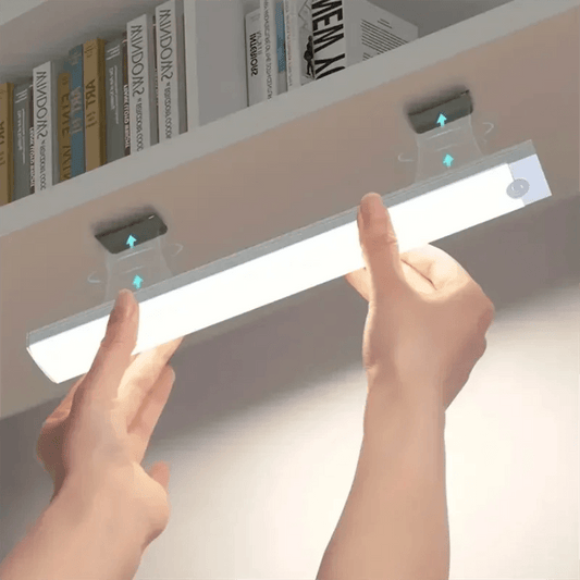 Hands installing an intelligent sensing light strip under a shelf for enhanced illumination